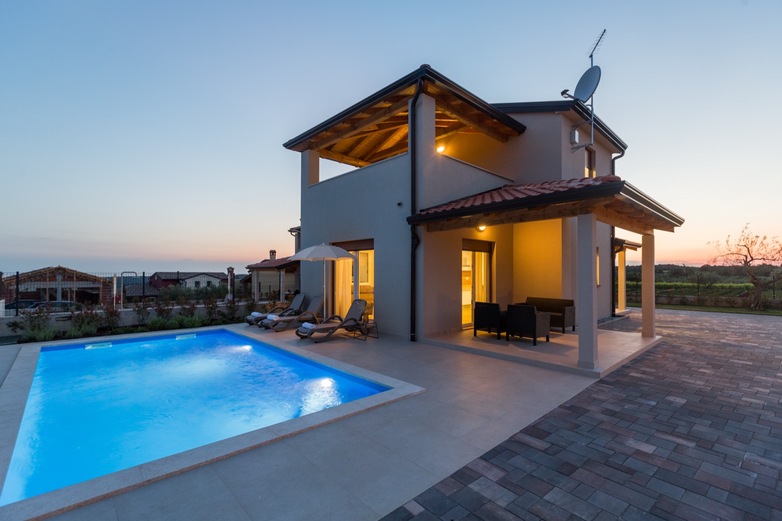 The villa and pool at blue hour, terrace lights on