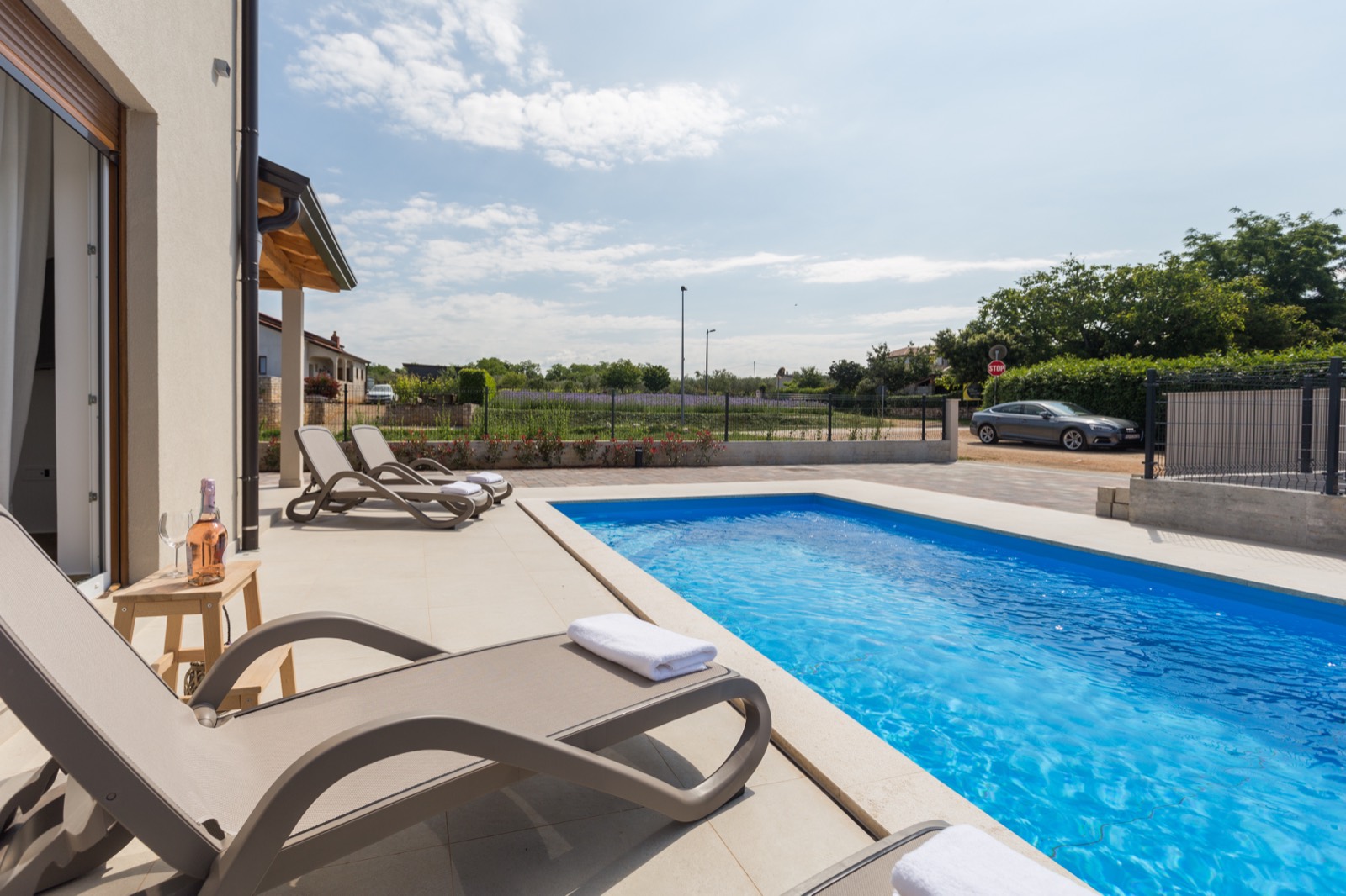 The 28 m² pool and sun loungers on the stone terrace at midday