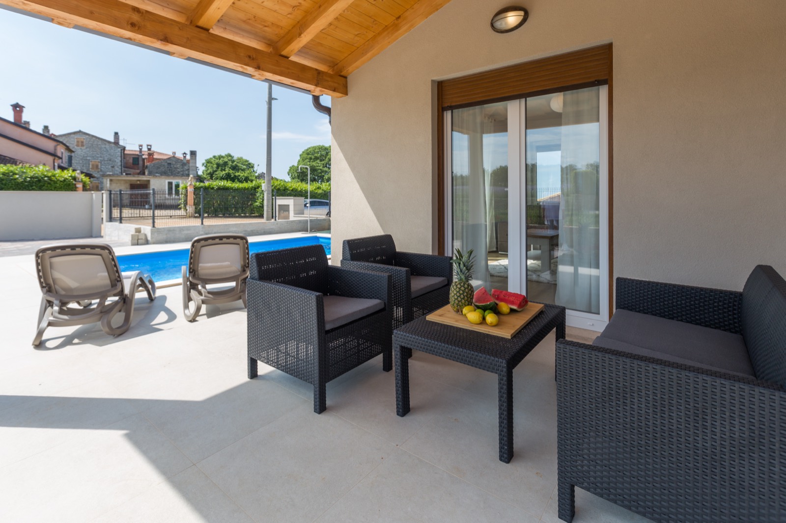 Covered outdoor lounge beside the pool under the timber roof